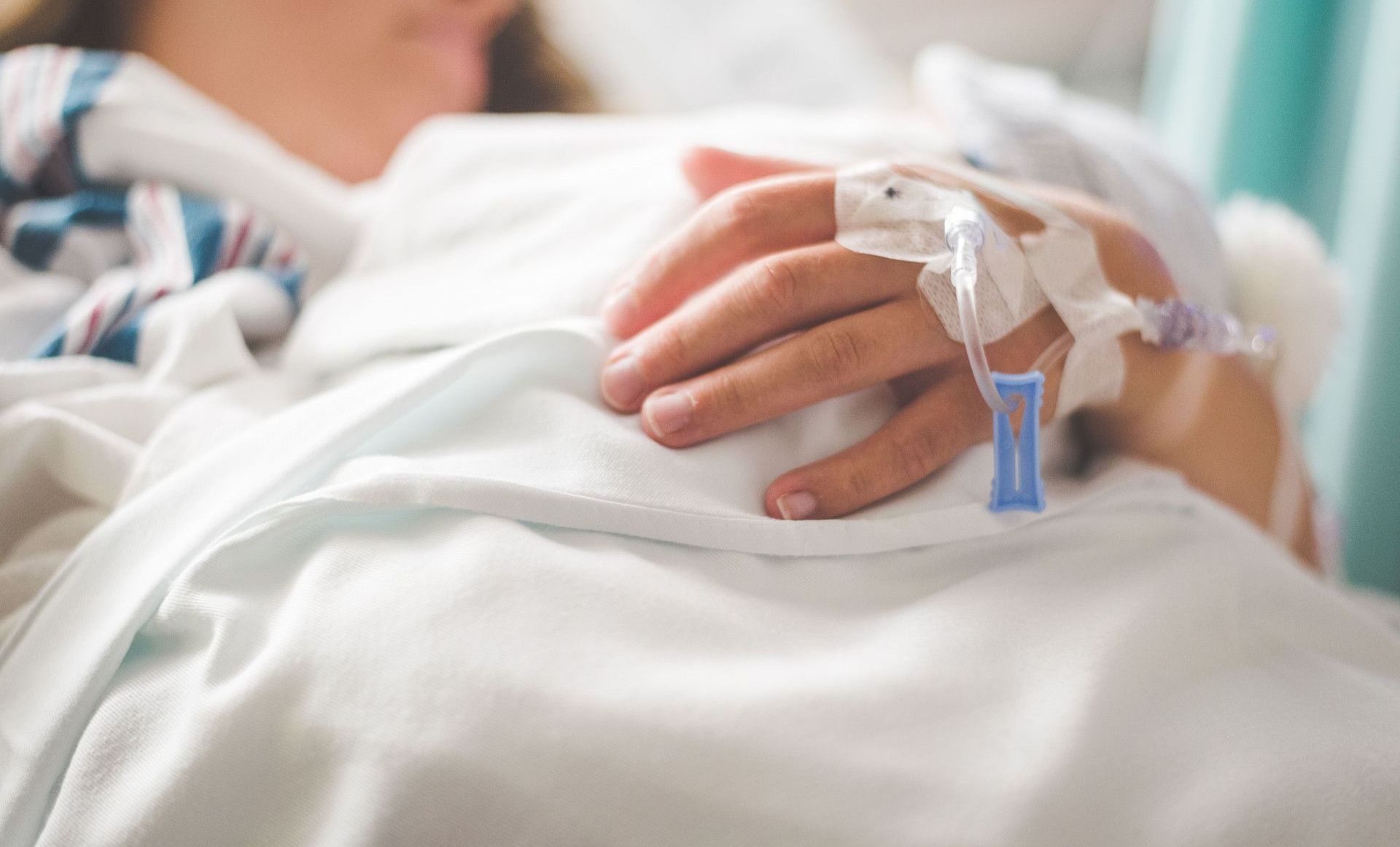 Focused shot of a patient's hand with IV in a hospital setting.